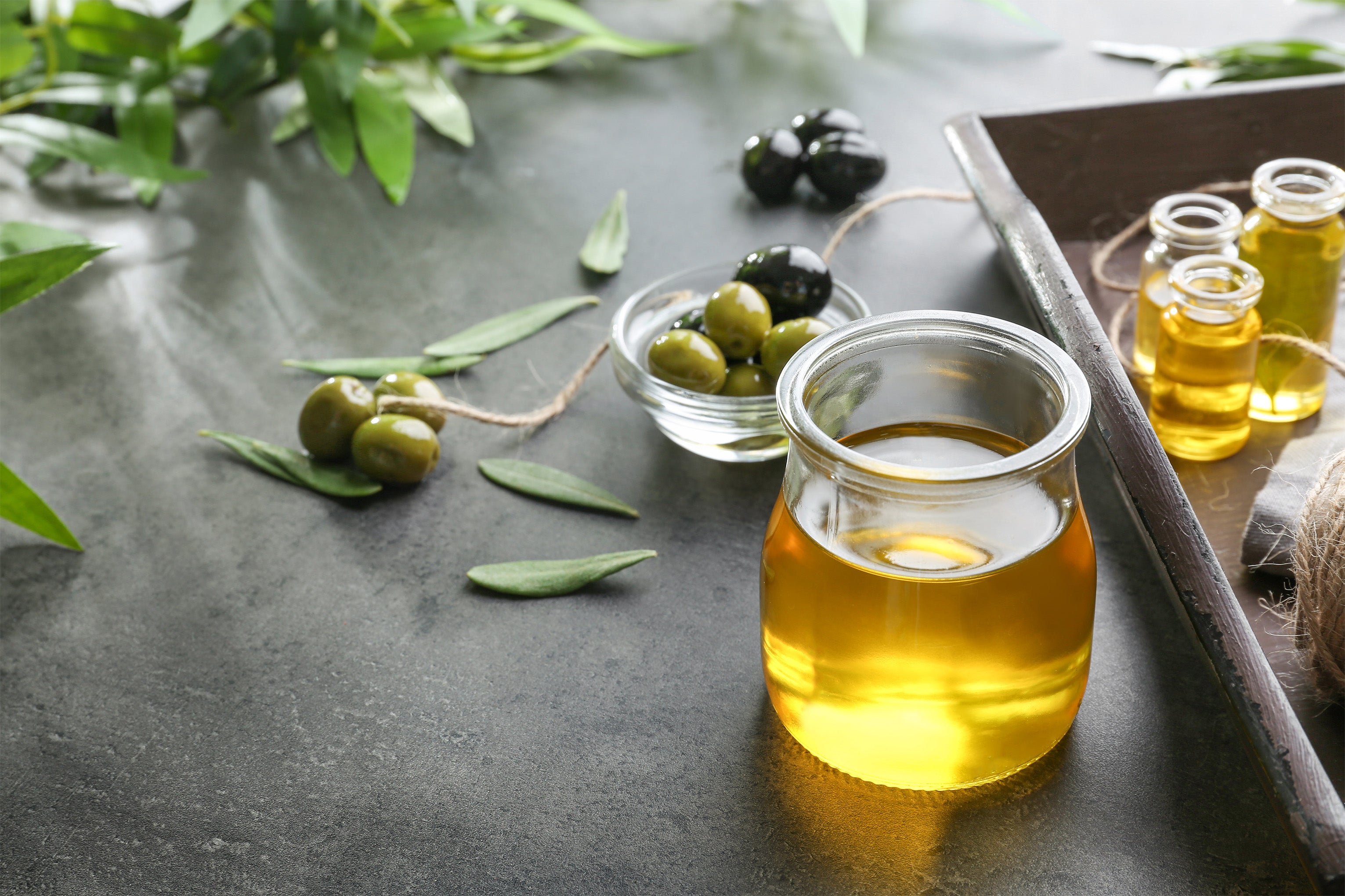 Kalamata Olivenöl naturbelassen in Glas neben Oliven in Schale